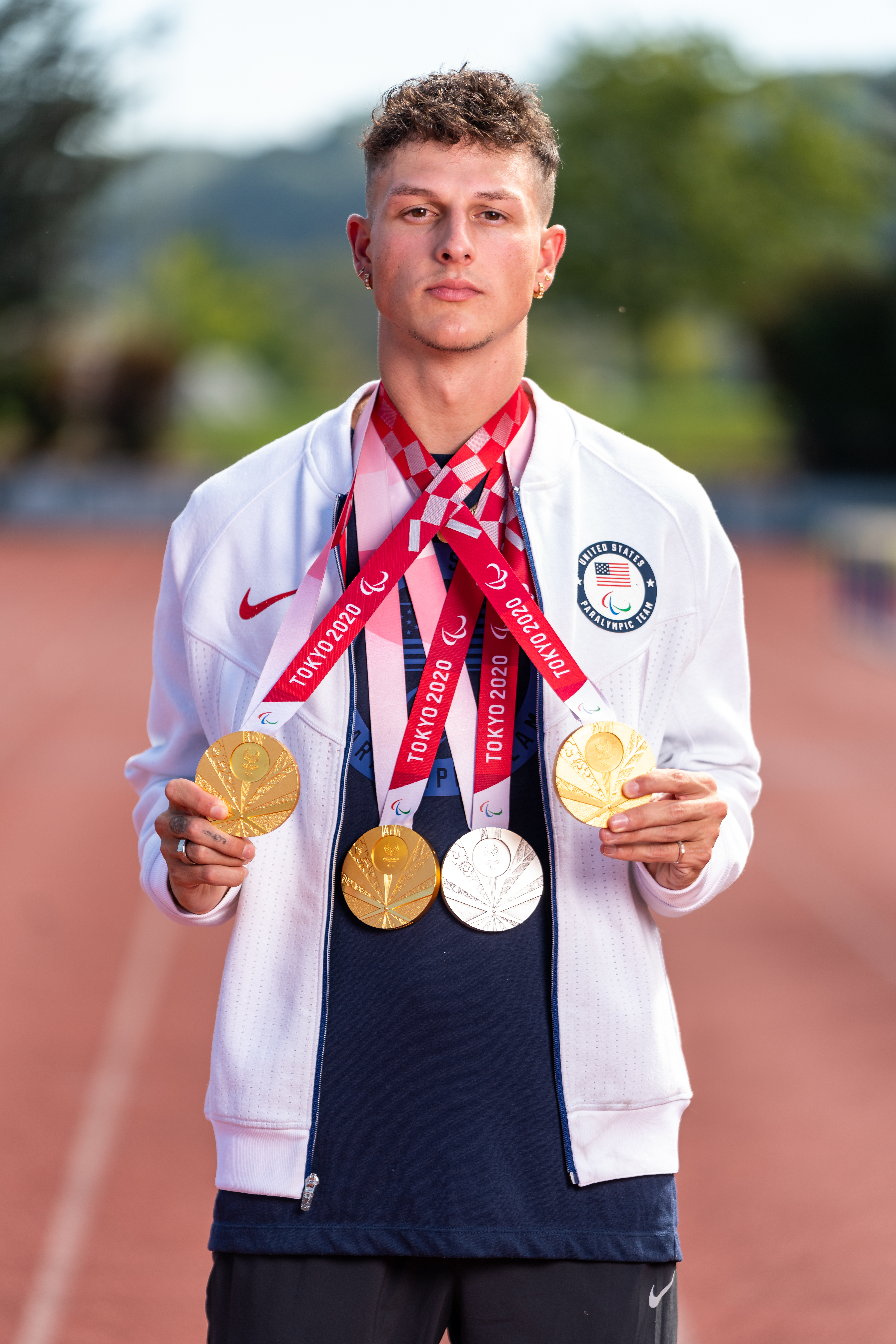 Nick Mayhugh wearing three gold medals and one silver medal